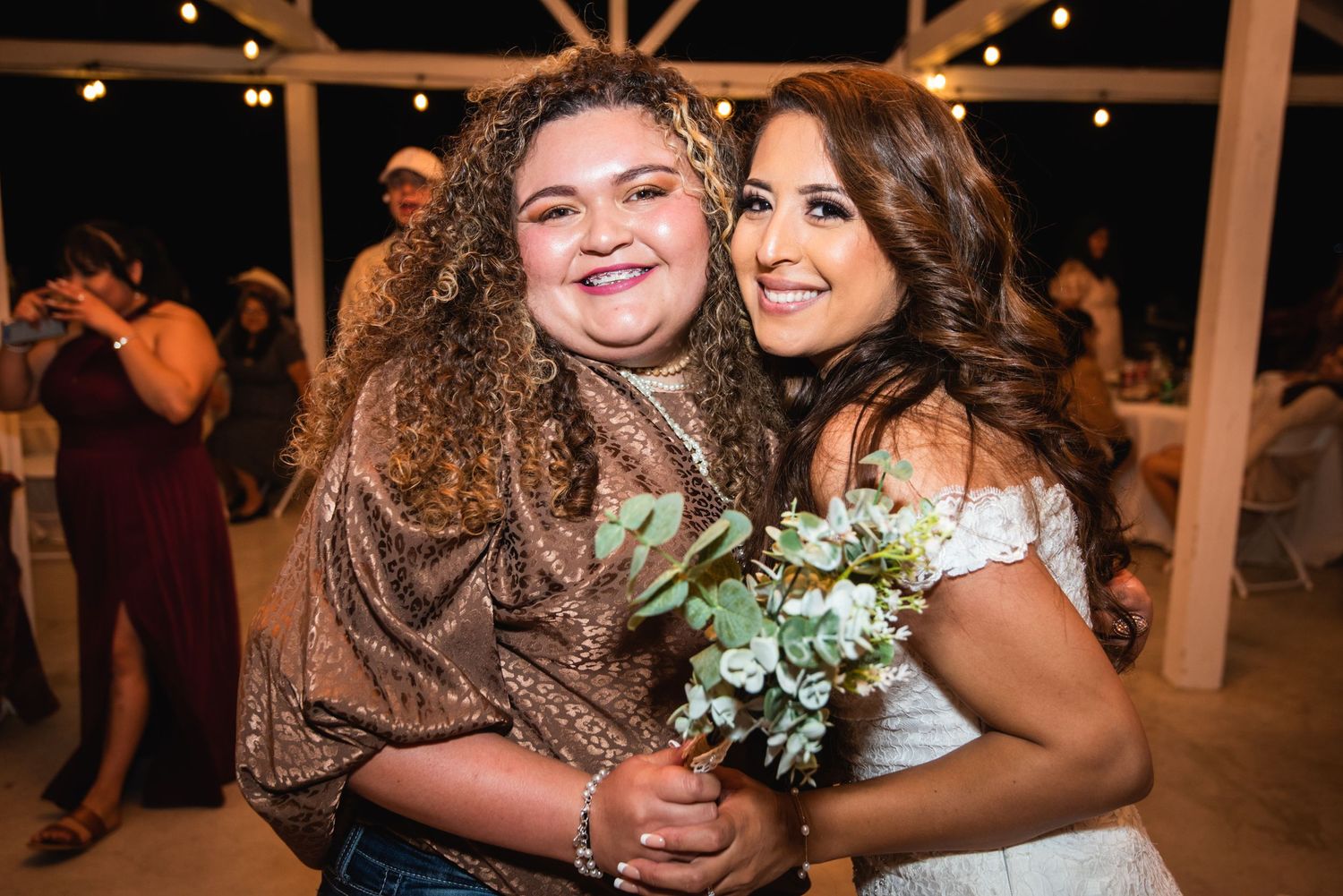 Wedding celebration moment with guests sharing hugs and flowers in a rustic barn venue.