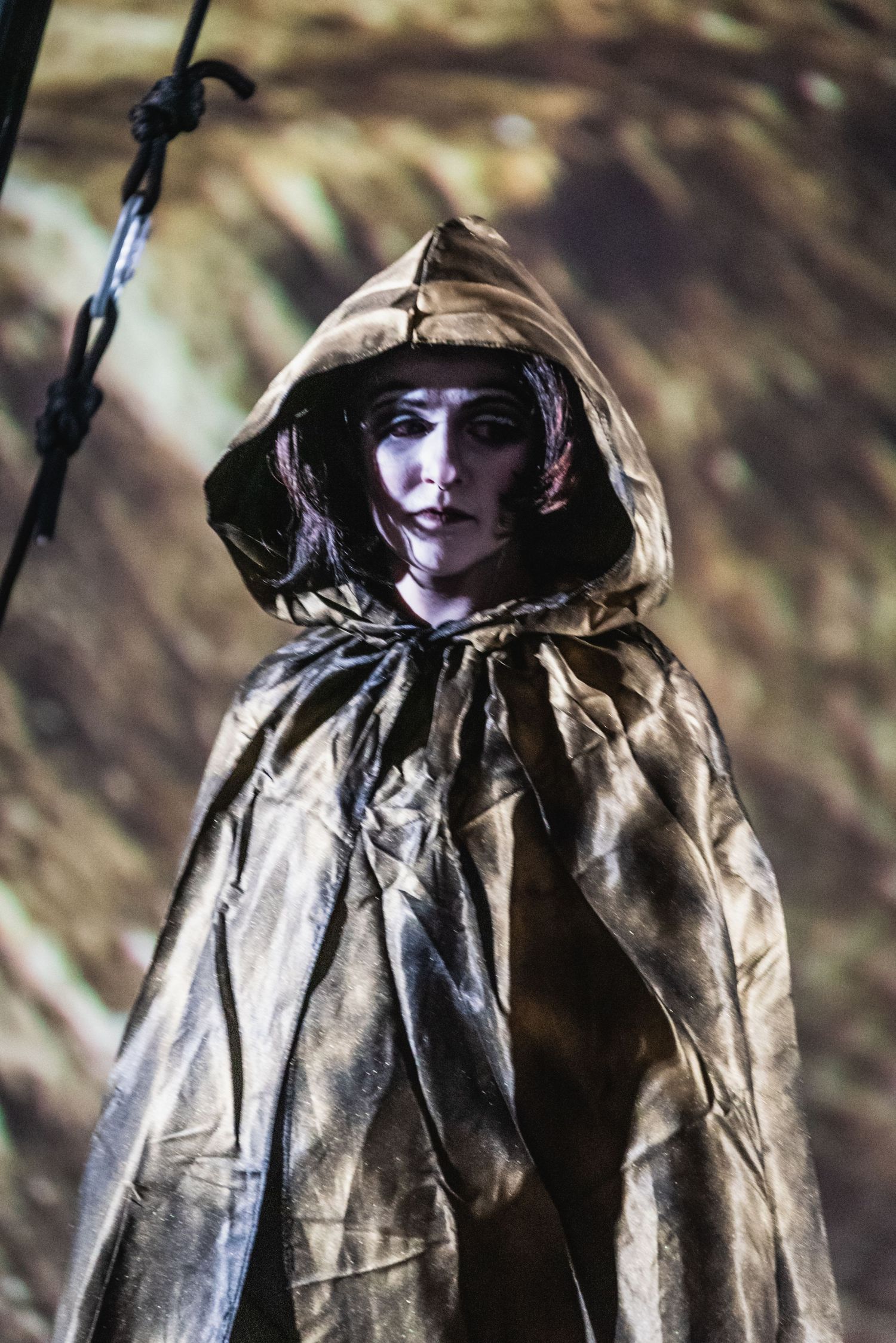 Figure in dramatic gold hooded cloak against atmospheric backdrop.