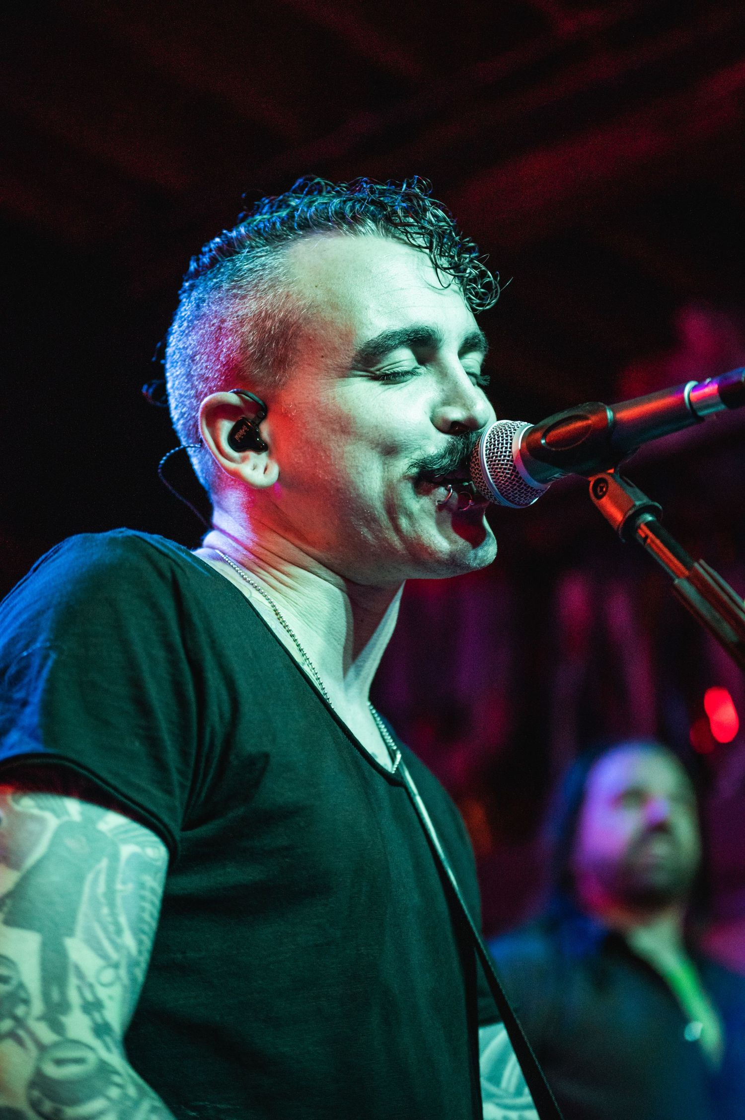 A musician performing on stage with dramatic blue and red concert lighting.