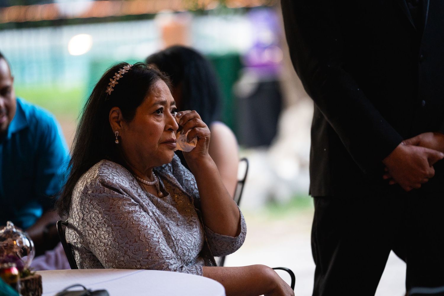 A guest in a sequined dress shows emotion during a wedding reception moment.