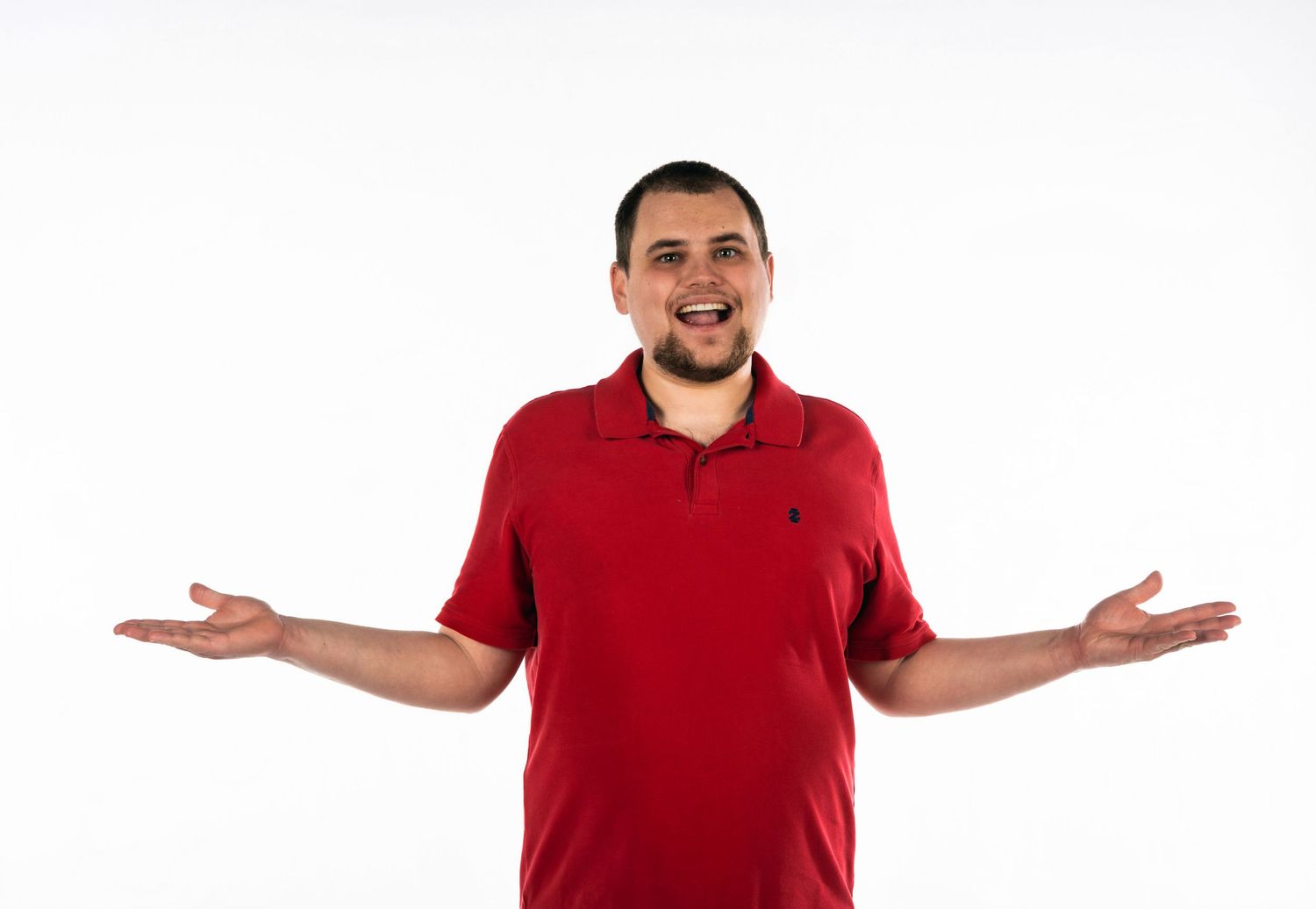 Person in red polo shirt gesturing with open arms against white background.