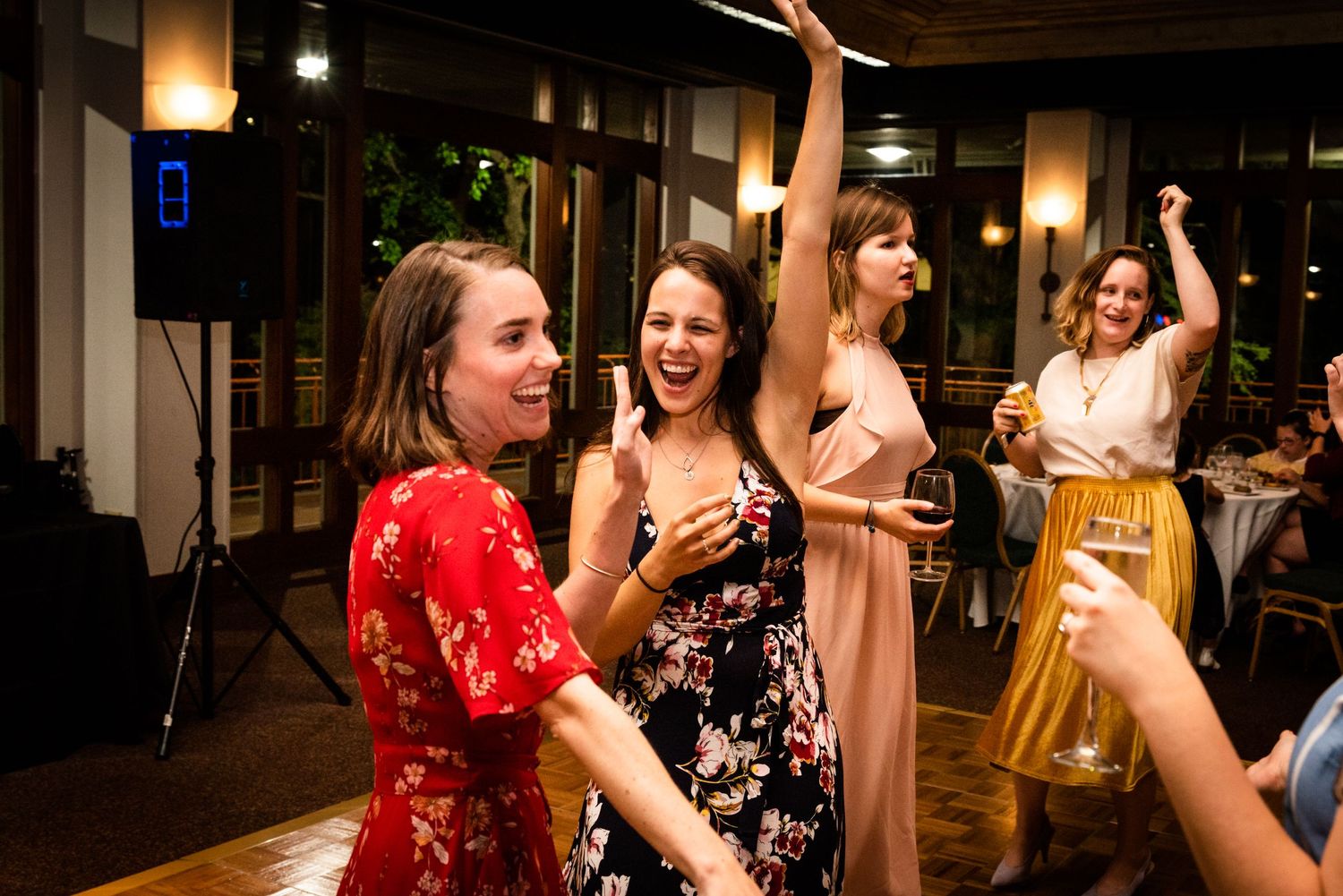 Wedding guests dancing and celebrating with raised arms at an indoor reception.