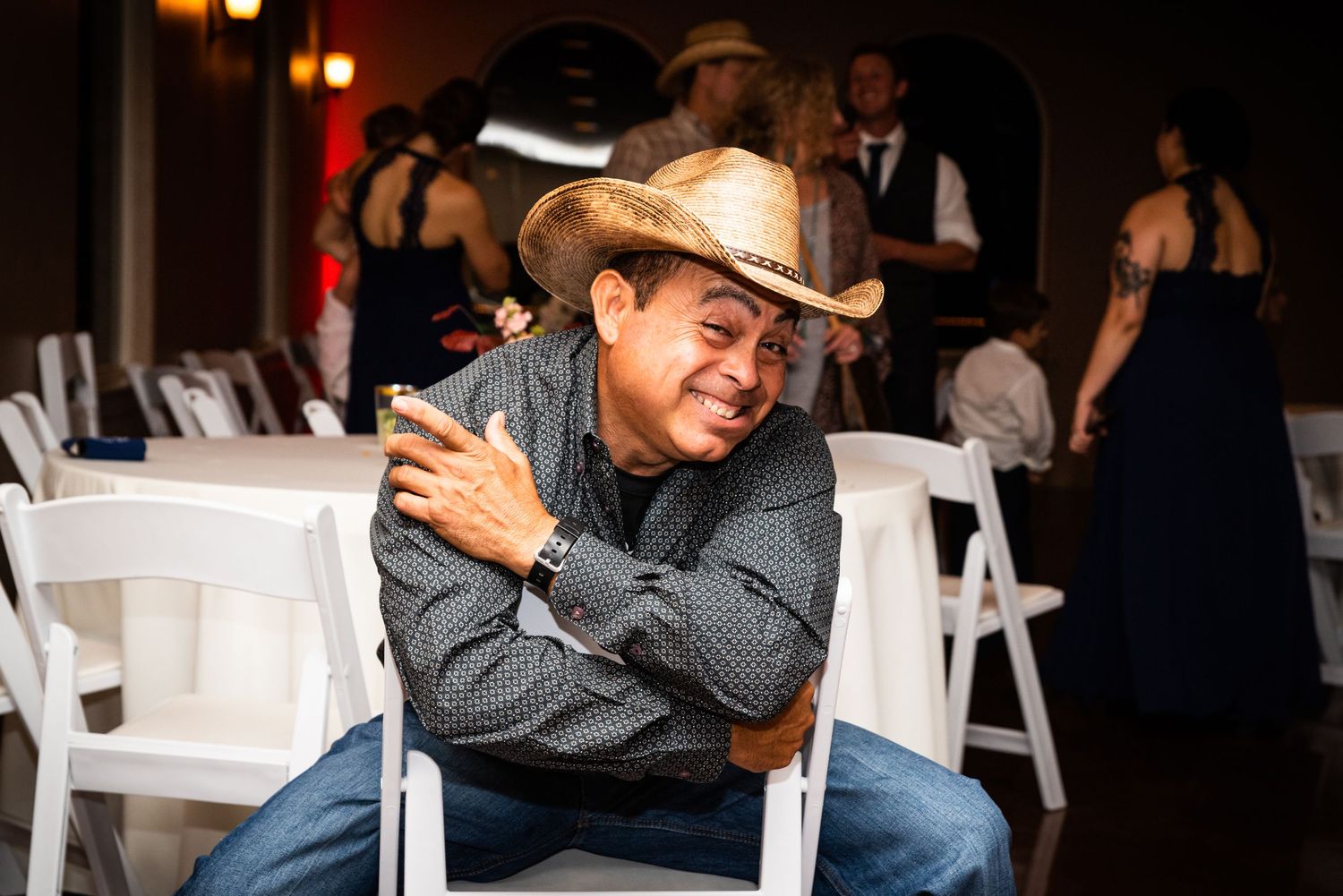 Guest in cowboy hat relaxes in chair during wedding reception.