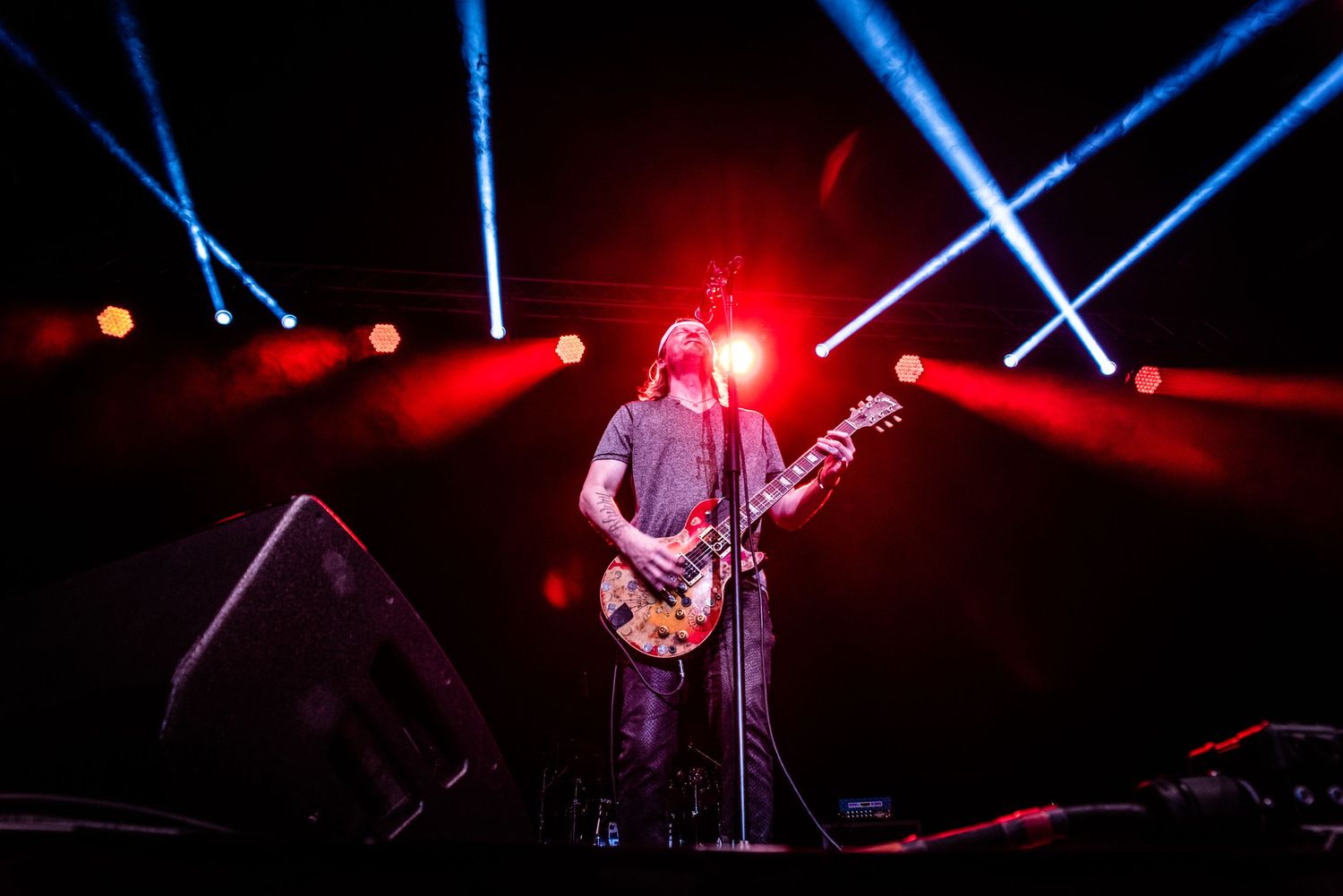 Stage performer silhouetted against dramatic red and blue concert lighting.