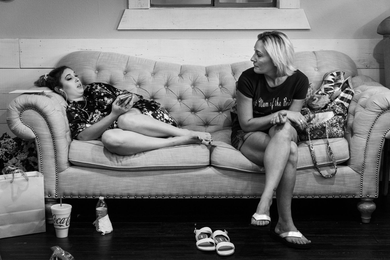 Two friends having conversation while relaxing on vintage tufted couch.