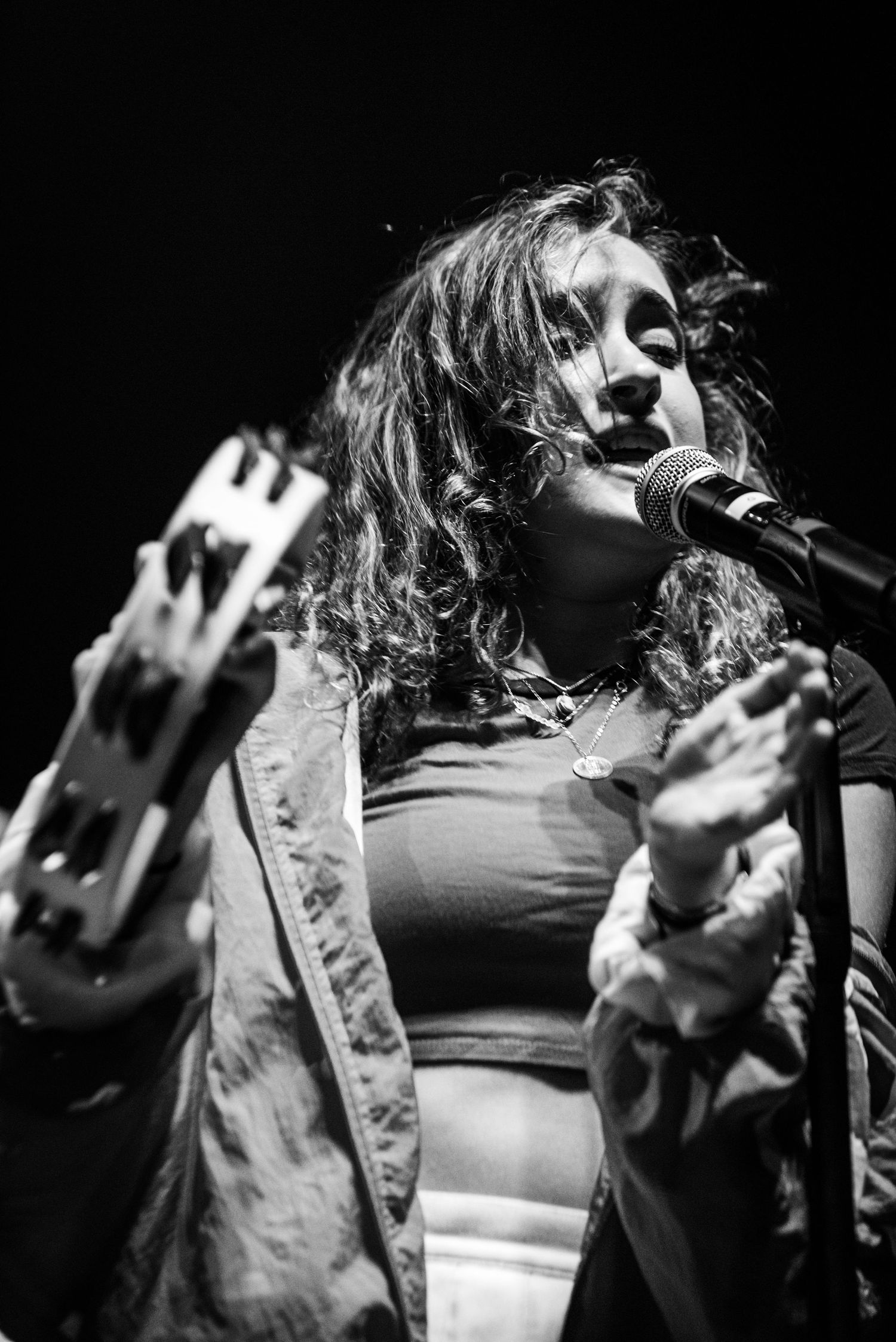 Black and white concert photo showing performer singing passionately into microphone.
