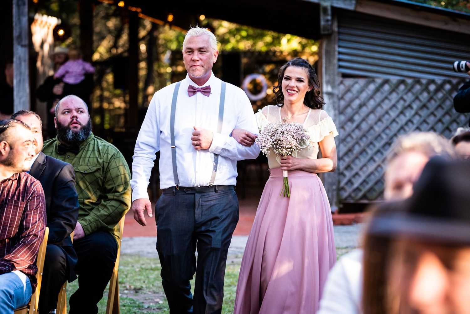 Wedding guests enjoy festivities at an outdoor reception with pink decor.