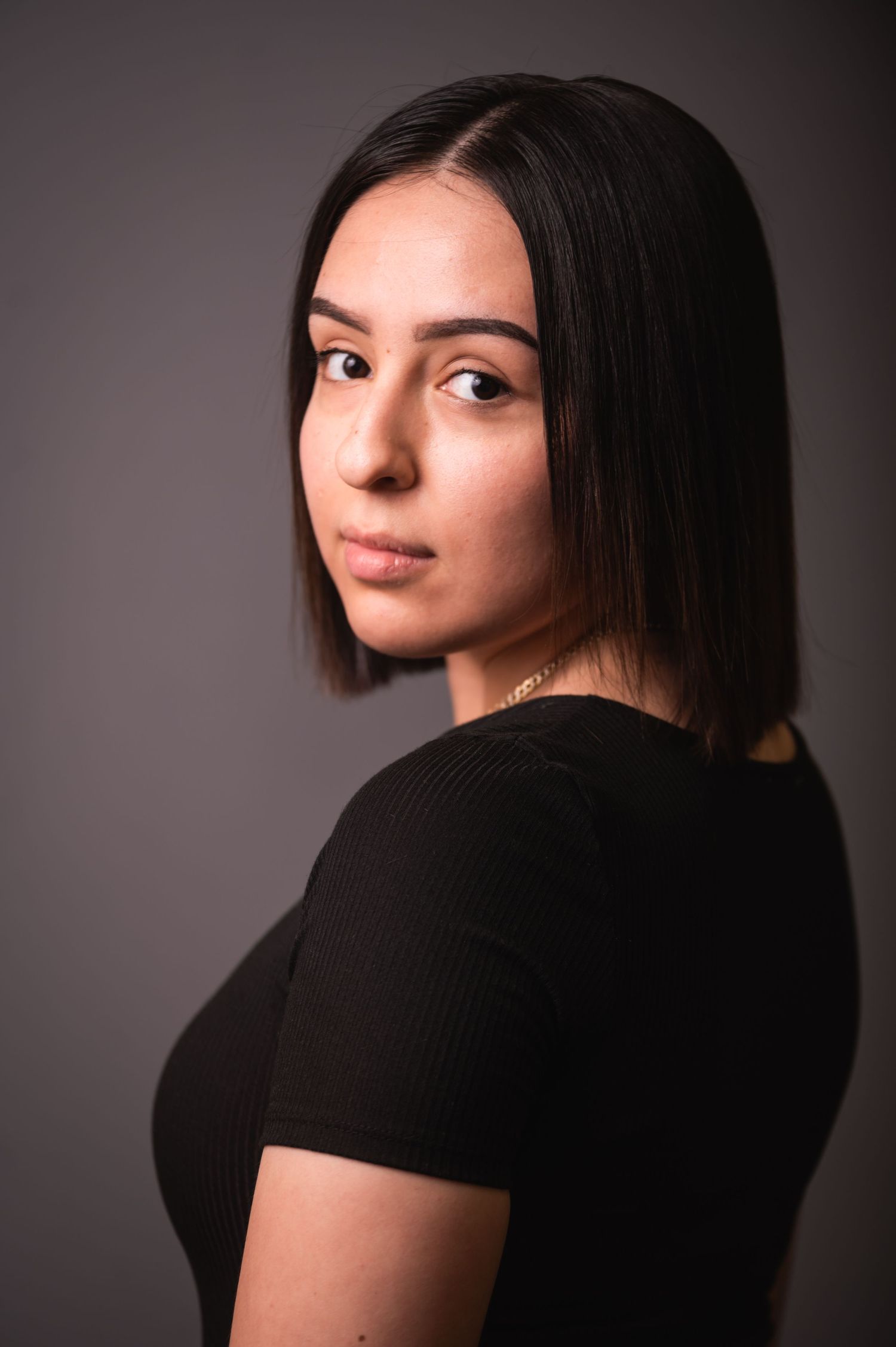 Artistic profile portrait of woman with short dark hair wearing black top in moody lighting.