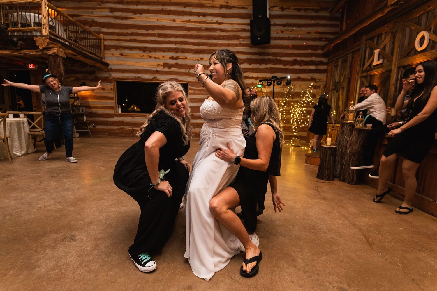 Wedding guests dancing and celebrating enthusiastically at a rustic barn reception.