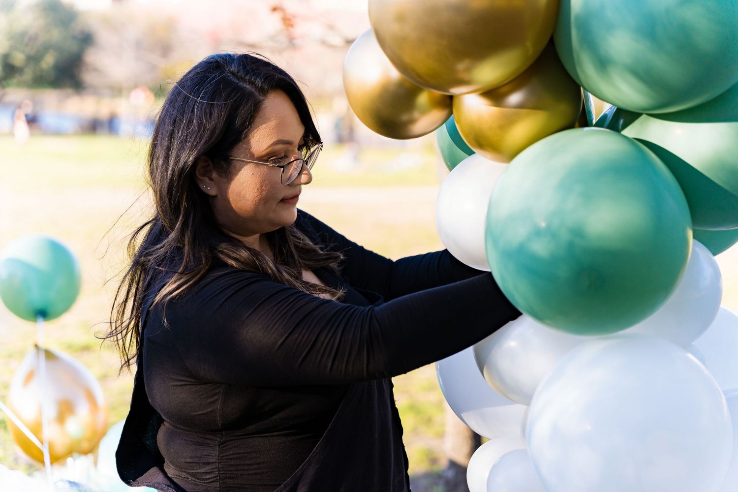 Elegant balloon arrangement featuring mint green and gold spheres in natural outdoor lighting.