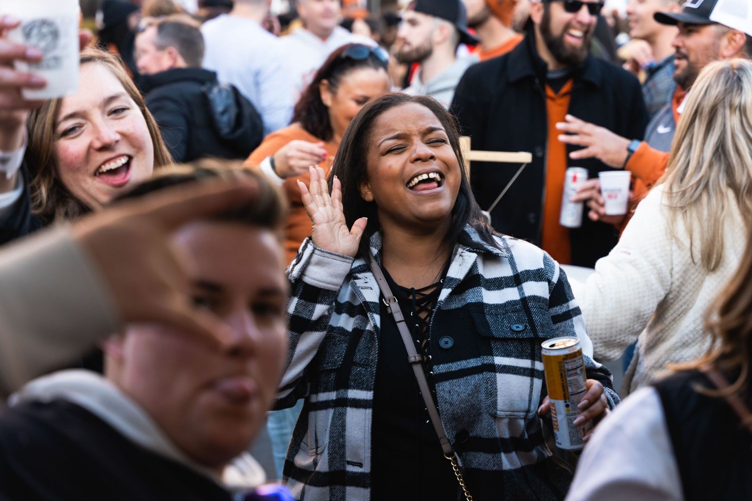 People laughing and celebrating in a crowded outdoor party atmosphere.