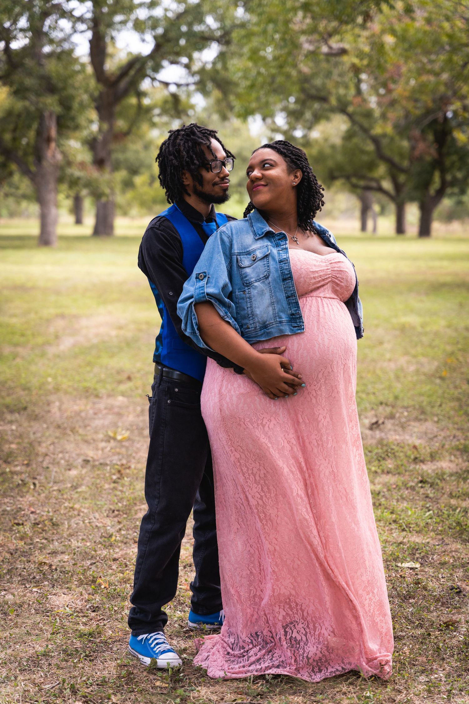Loving couple embraces in park during maternity photo session.