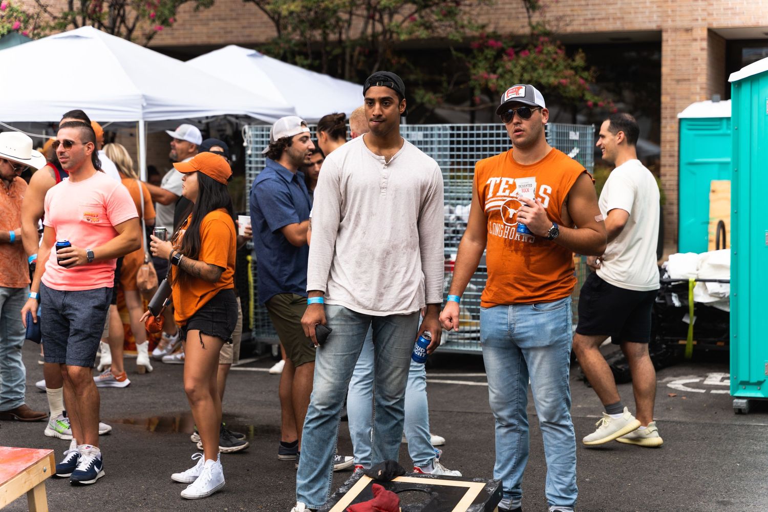 Festival attendees in casual attire gathered near portable restrooms at an outdoor event.