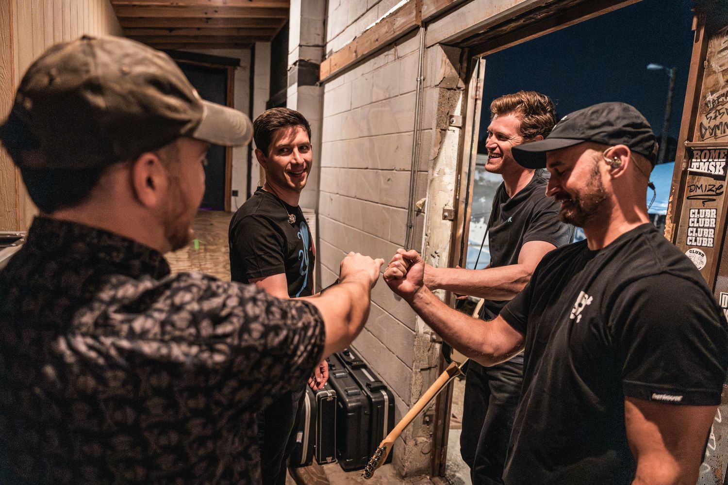 A group of people greeting each other with a fist bump outside a building entrance.