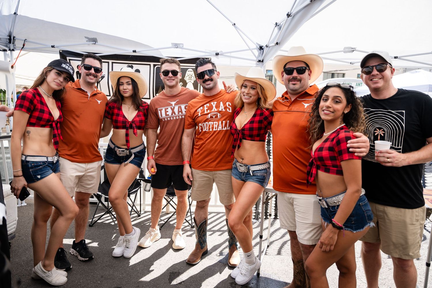 Group photo of Texas sports fans in orange jerseys and casual attire at outdoor event.