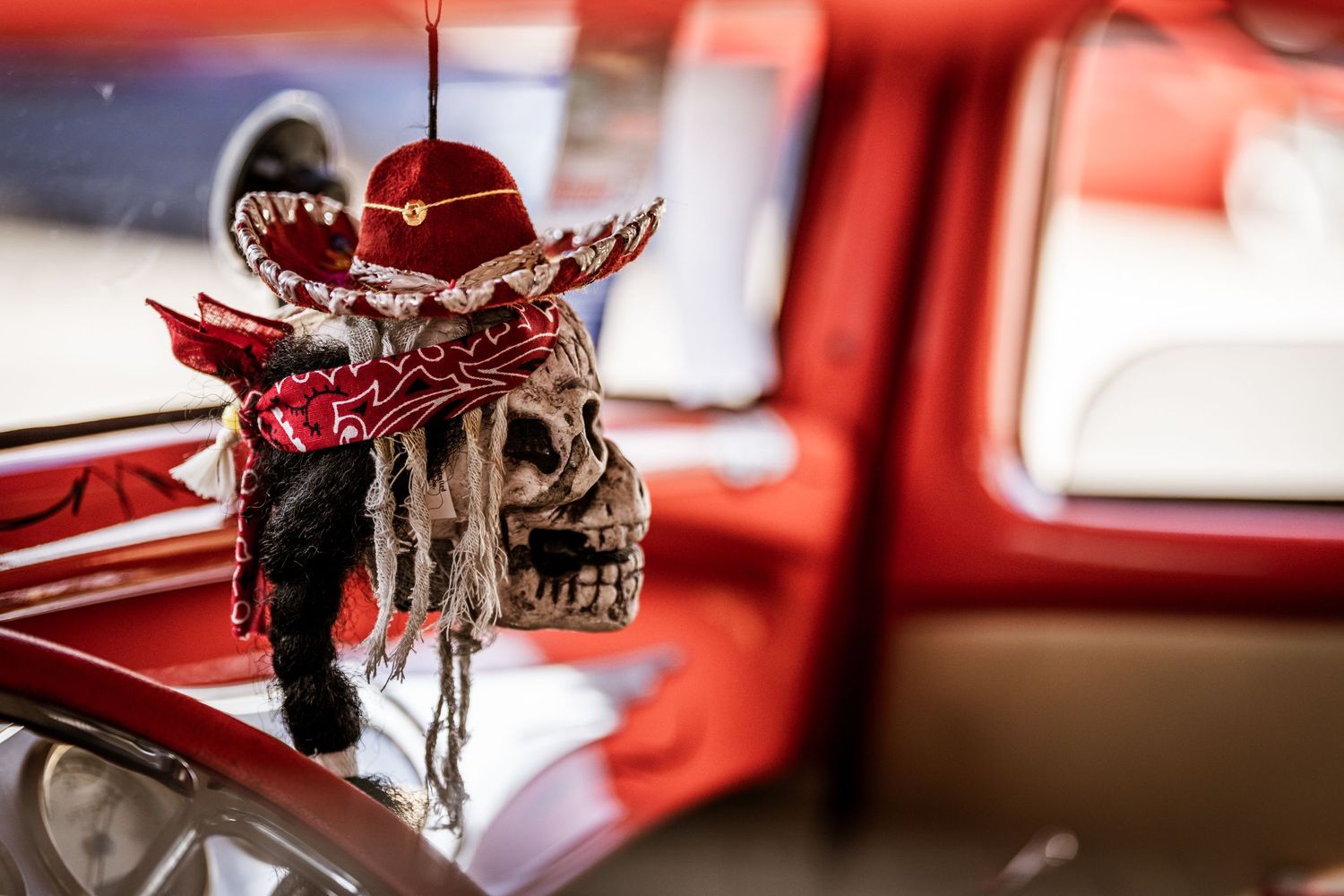 Decorative red and black skull ornament on classic car dashboard.