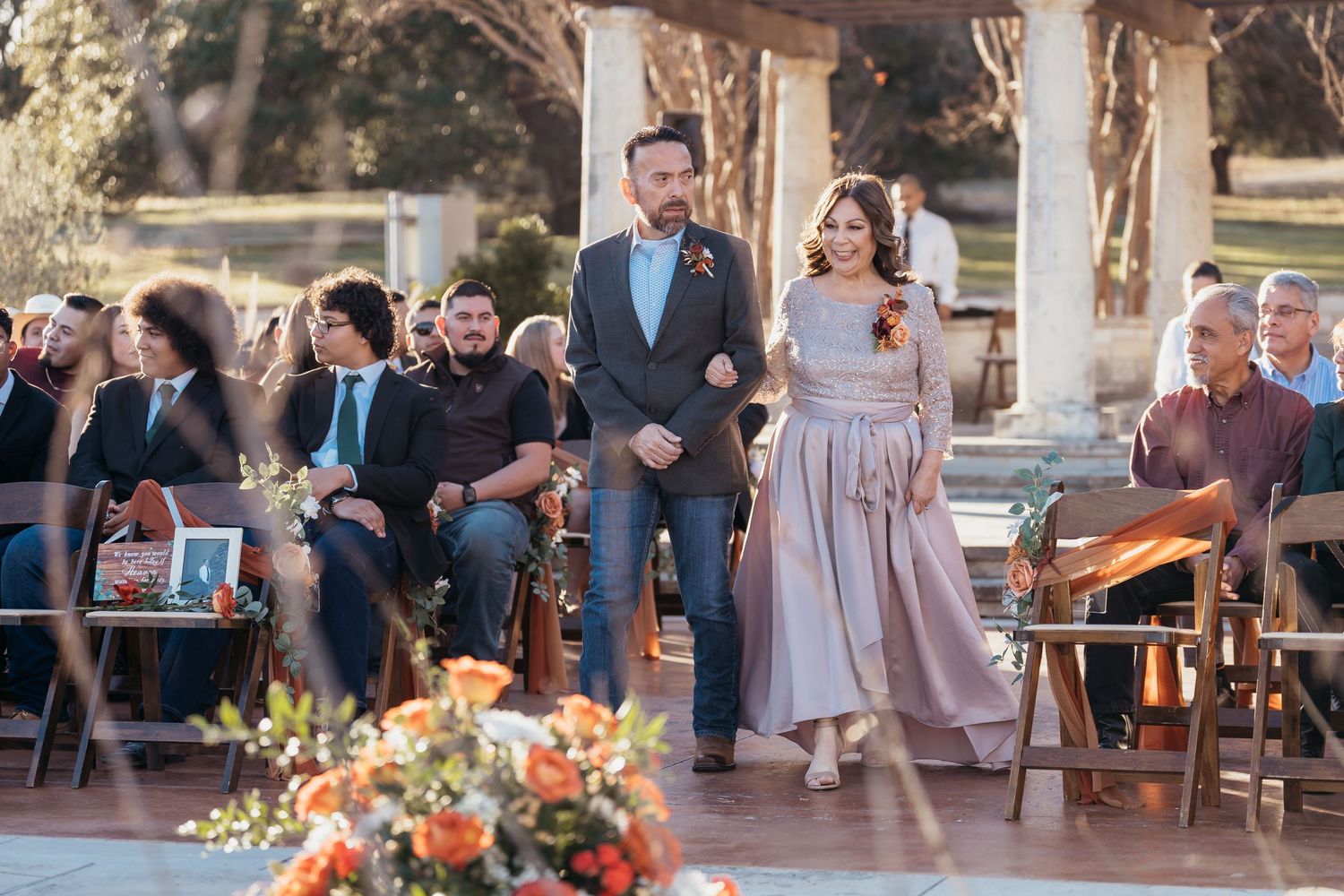 Wedding ceremony setup with guests seated and couple standing on rustic outdoor platform.