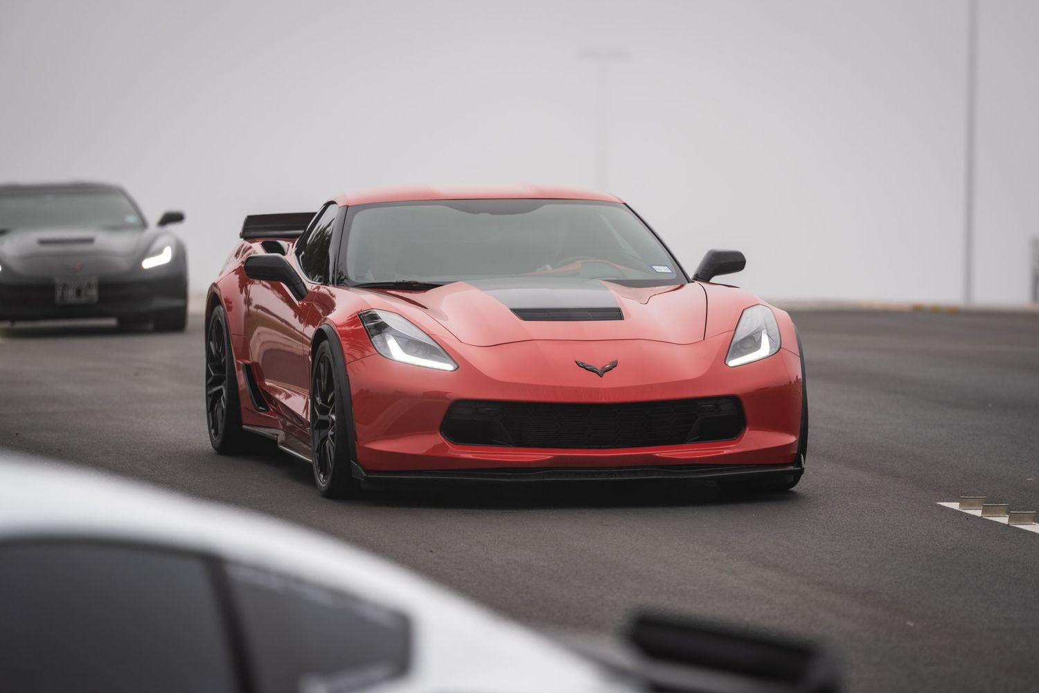 Red Chevrolet Corvette Z06 with aggressive aerodynamic modifications on track.