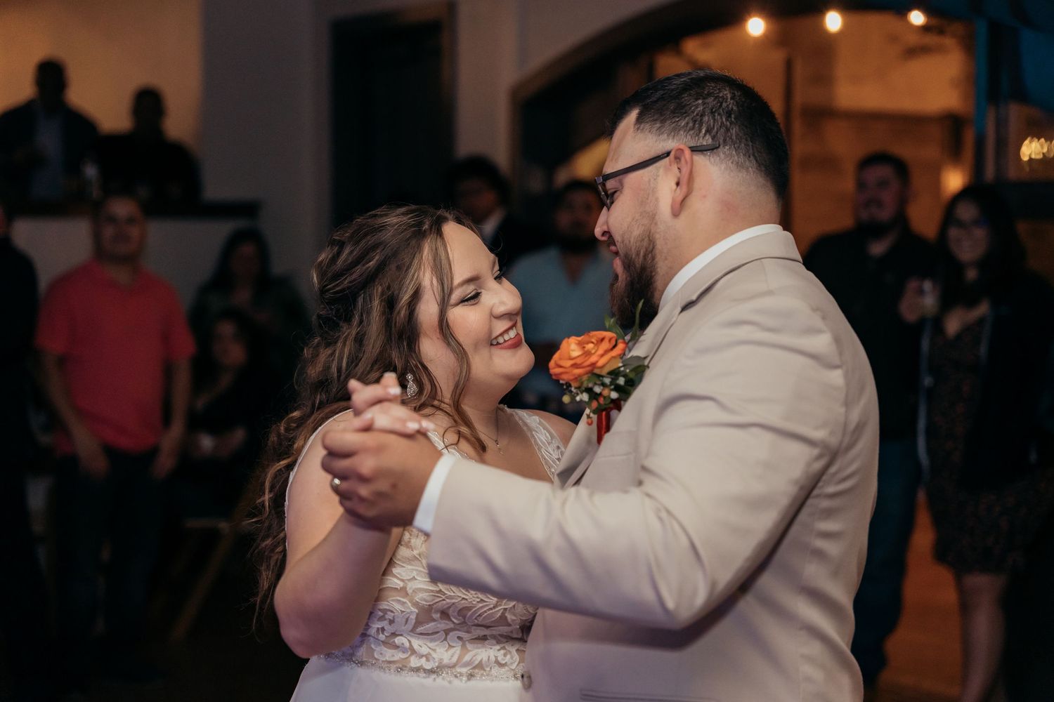 A romantic moment captured during a wedding dance with soft lighting and guests watching.