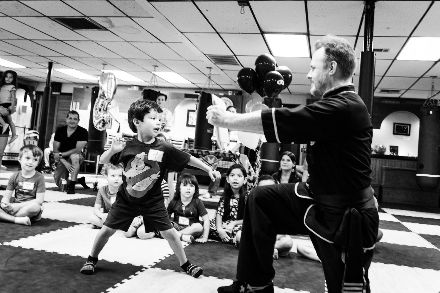 People training in a martial arts studio practicing self-defense and grappling techniques on exercise mats.