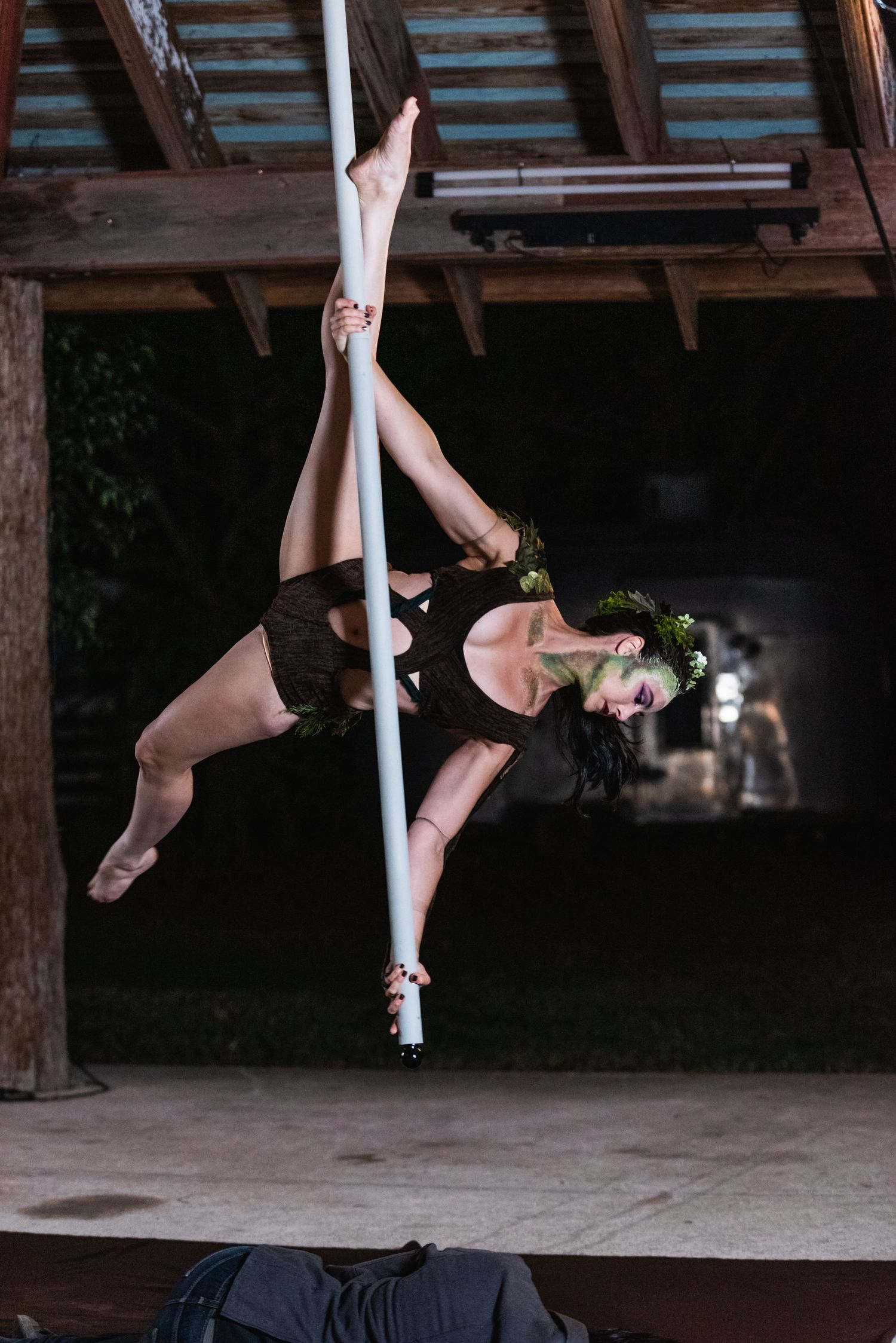 Aerial dancers perform graceful poses while suspended from white fabric under a rustic wooden beam structure.