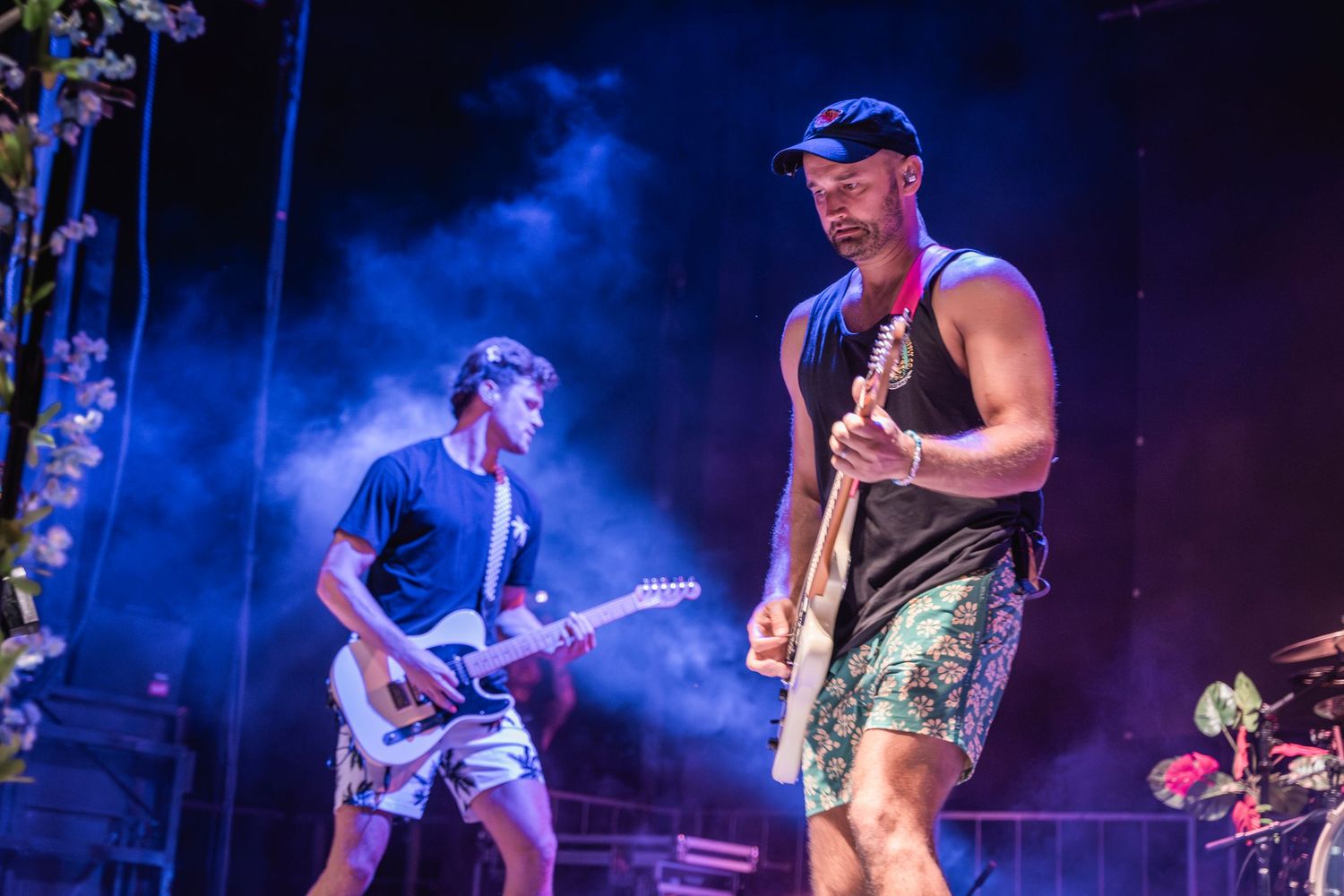Musicians perform on stage with dramatic blue lighting and fog effects during a live concert performance.