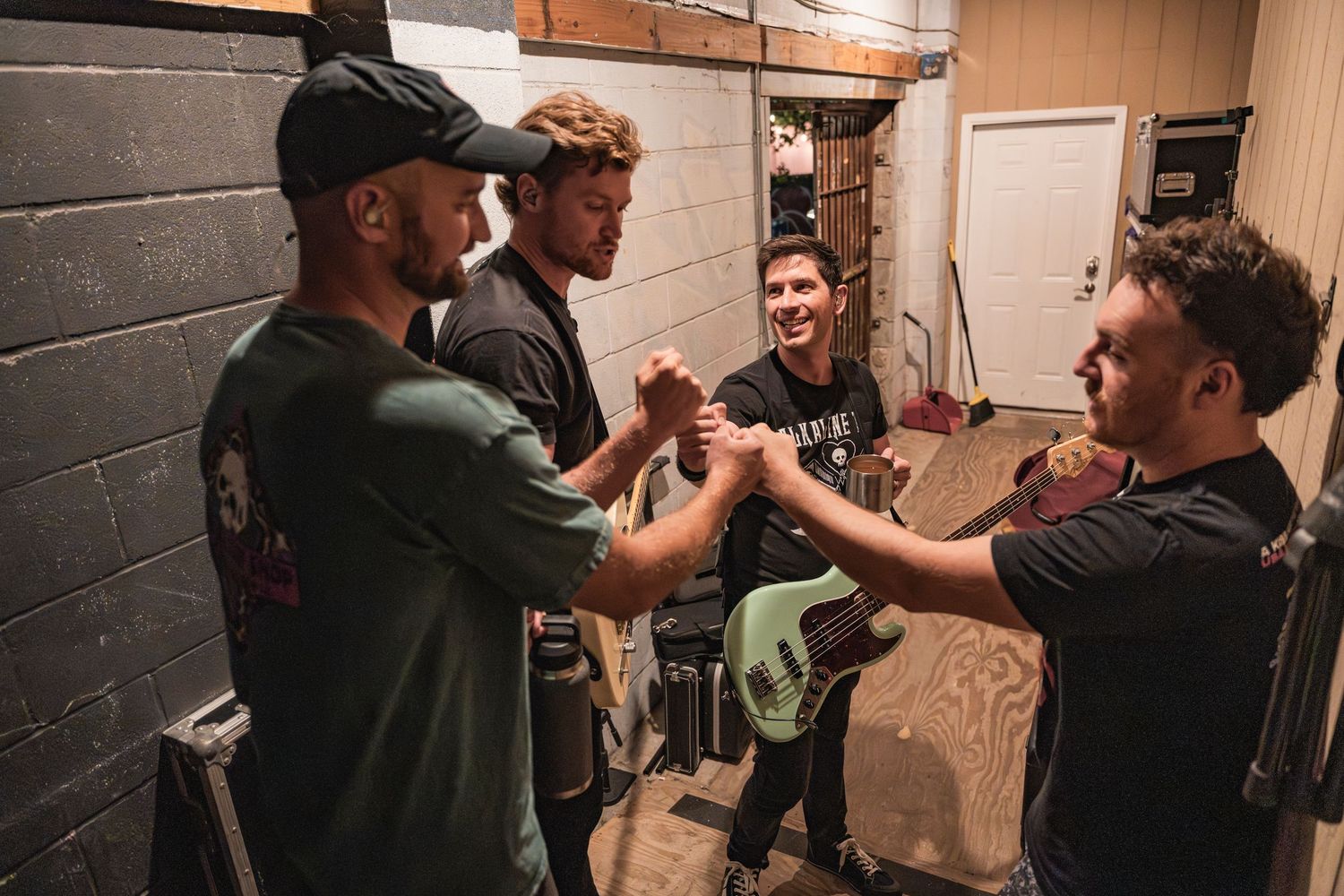 A group of people sharing an energetic moment backstage in a dimly lit brick hallway.