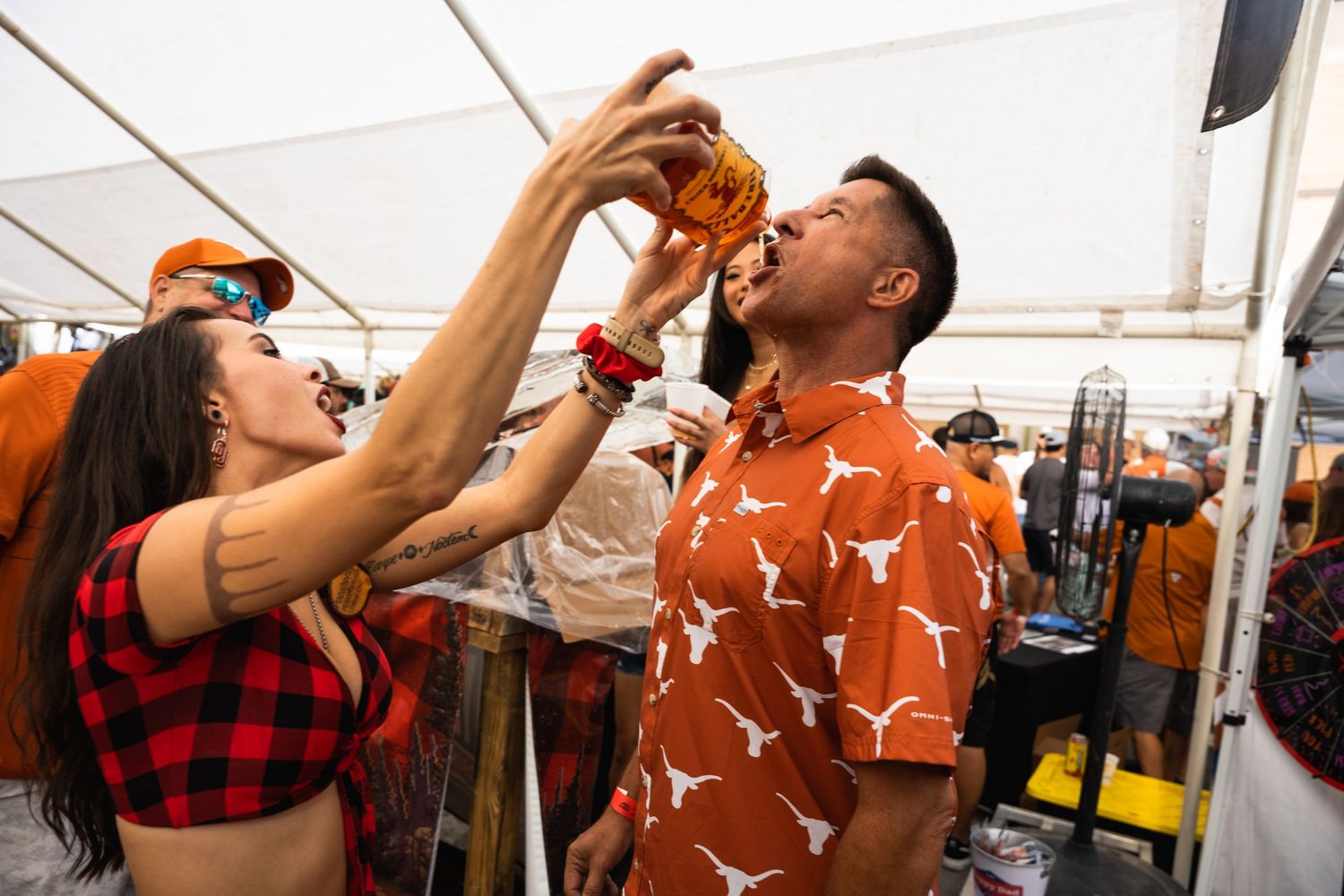 Two people in festive attire share food at an outdoor party.
