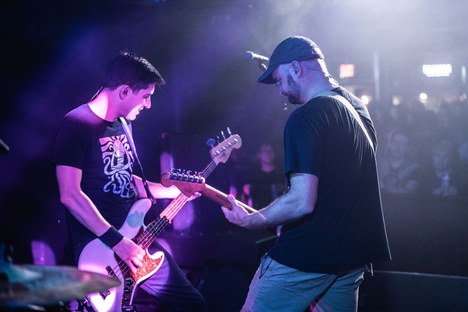 Two musicians performing together on stage with dramatic backlighting.