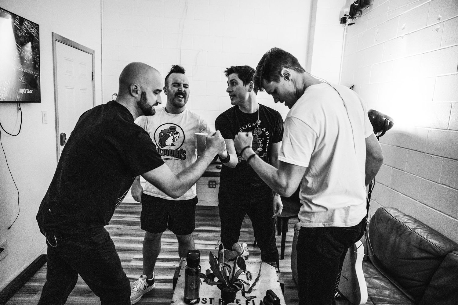 Black and white candid shot of band members interacting in a backstage area.