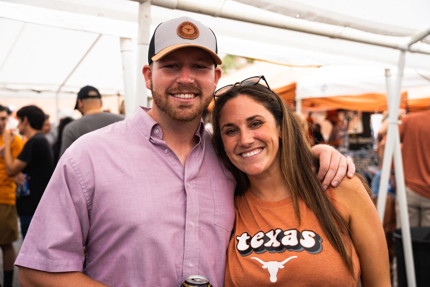 Couple in Texas Longhorns gear smiling together at a tailgate party.