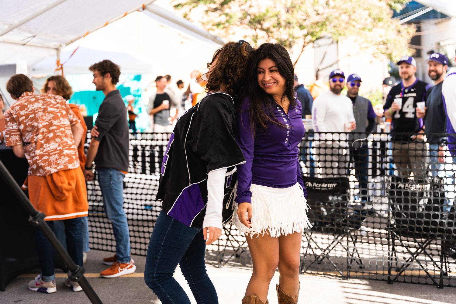 Two people dancing and having fun at an outdoor event with festival attendees in background.