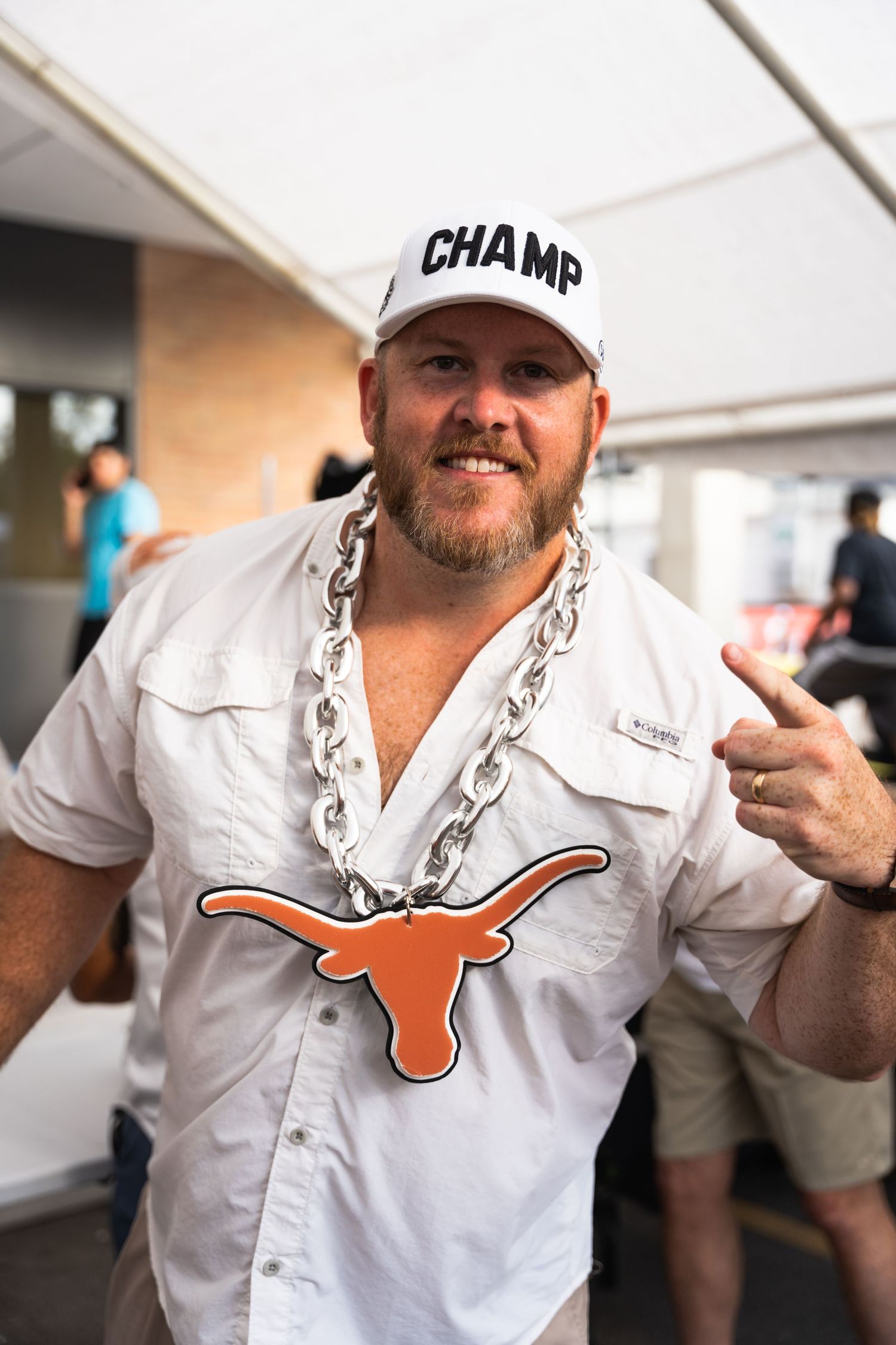 Texas Longhorns fan in a CHAMP hat and chain necklace poses at an outdoor event.