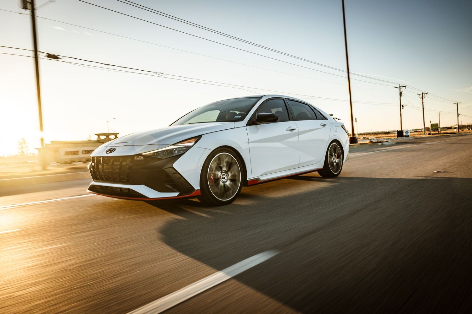 White Hyundai Sonata N-Line photographed in motion during golden hour.