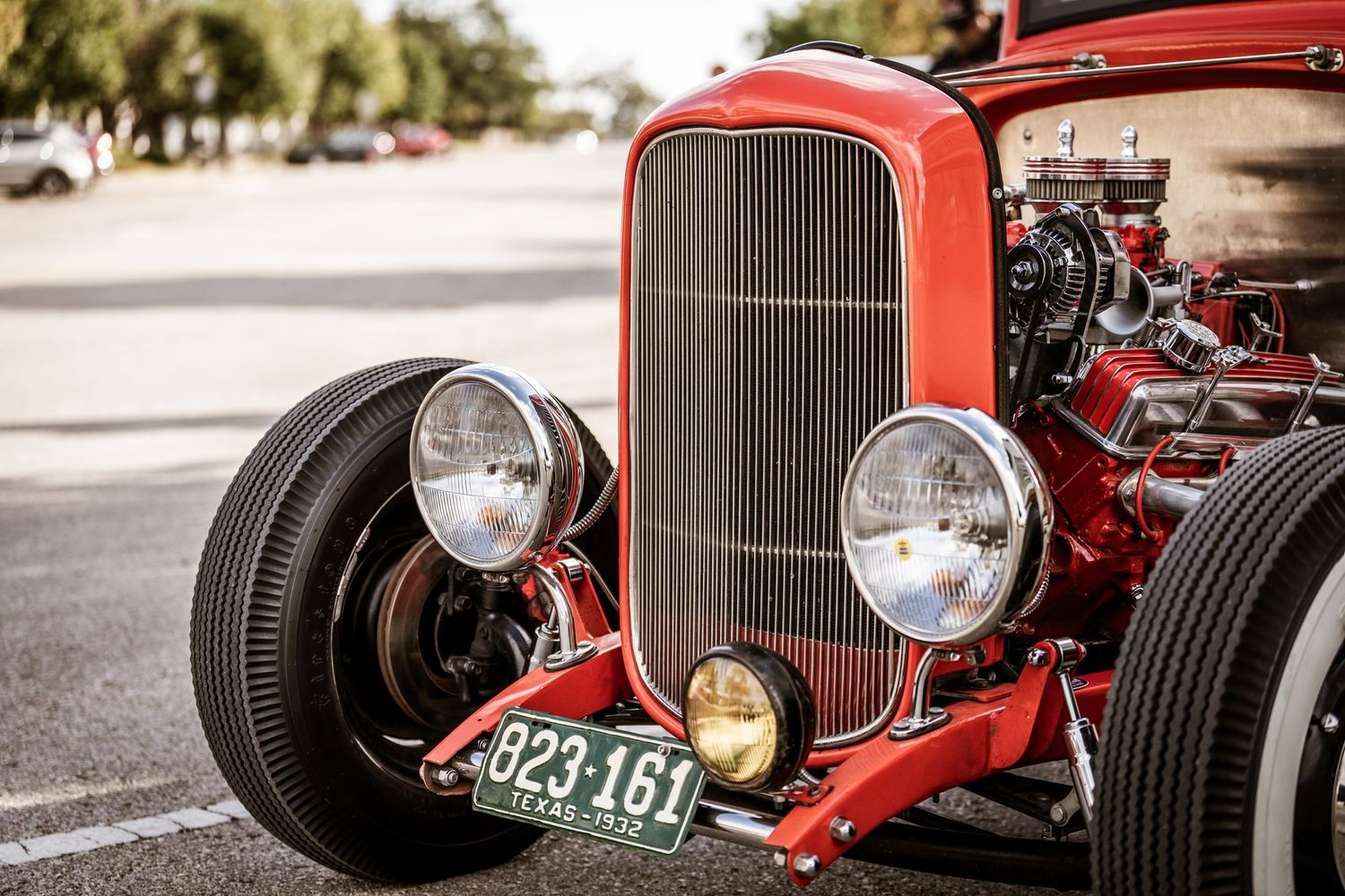 Classic red hot rod front end with vintage grille and headlamps.