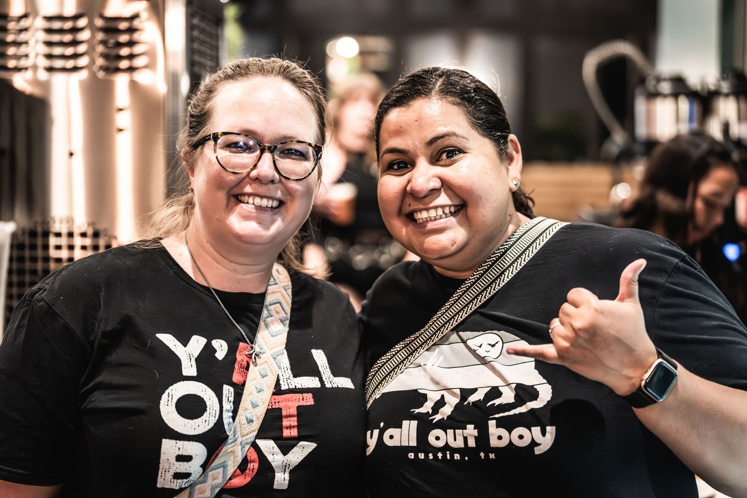 Two concert attendees wearing Yell Out Boy merchandise pose together with shaka signs.