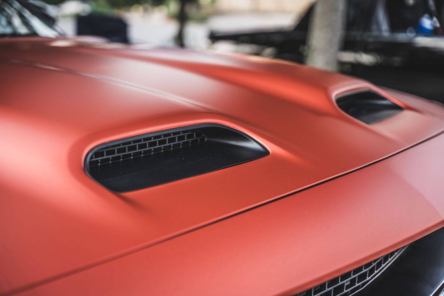 Close-up view of a red sports car hood with air intake vents.