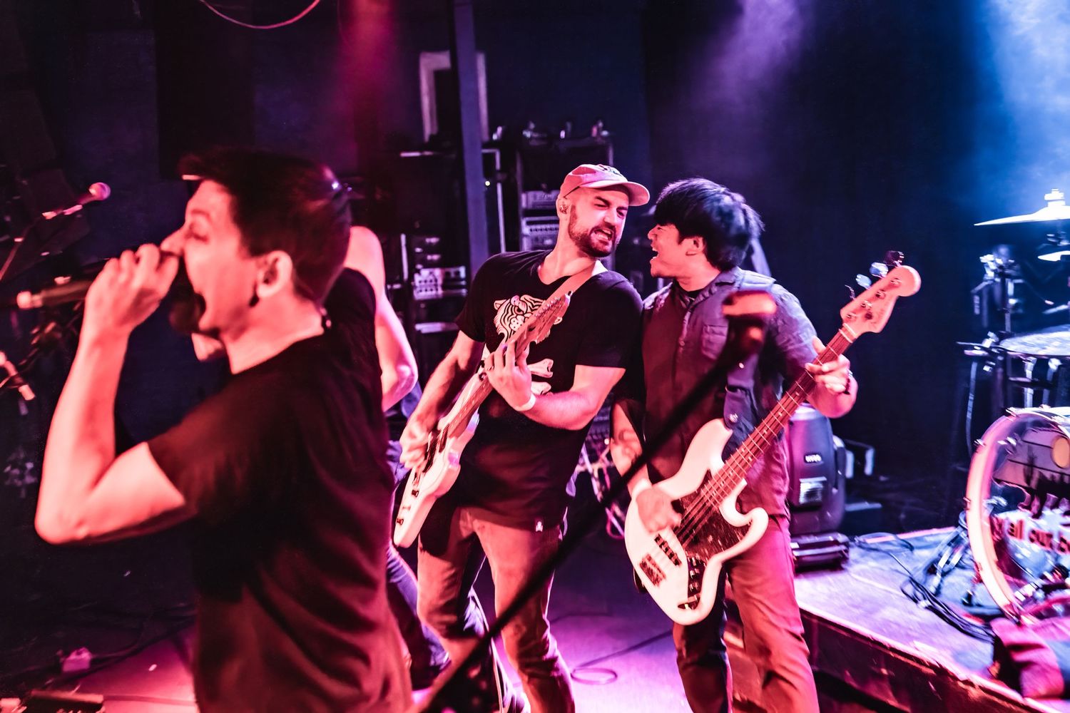 Band members perform intensely on stage under dramatic concert lighting.