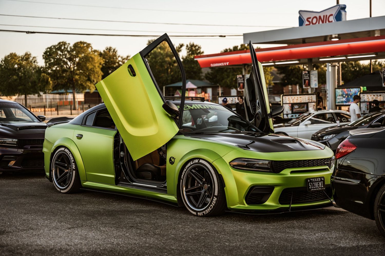 Lime green Dodge Charger with scissor doors and custom wheels parked at a Sonic Drive-In.