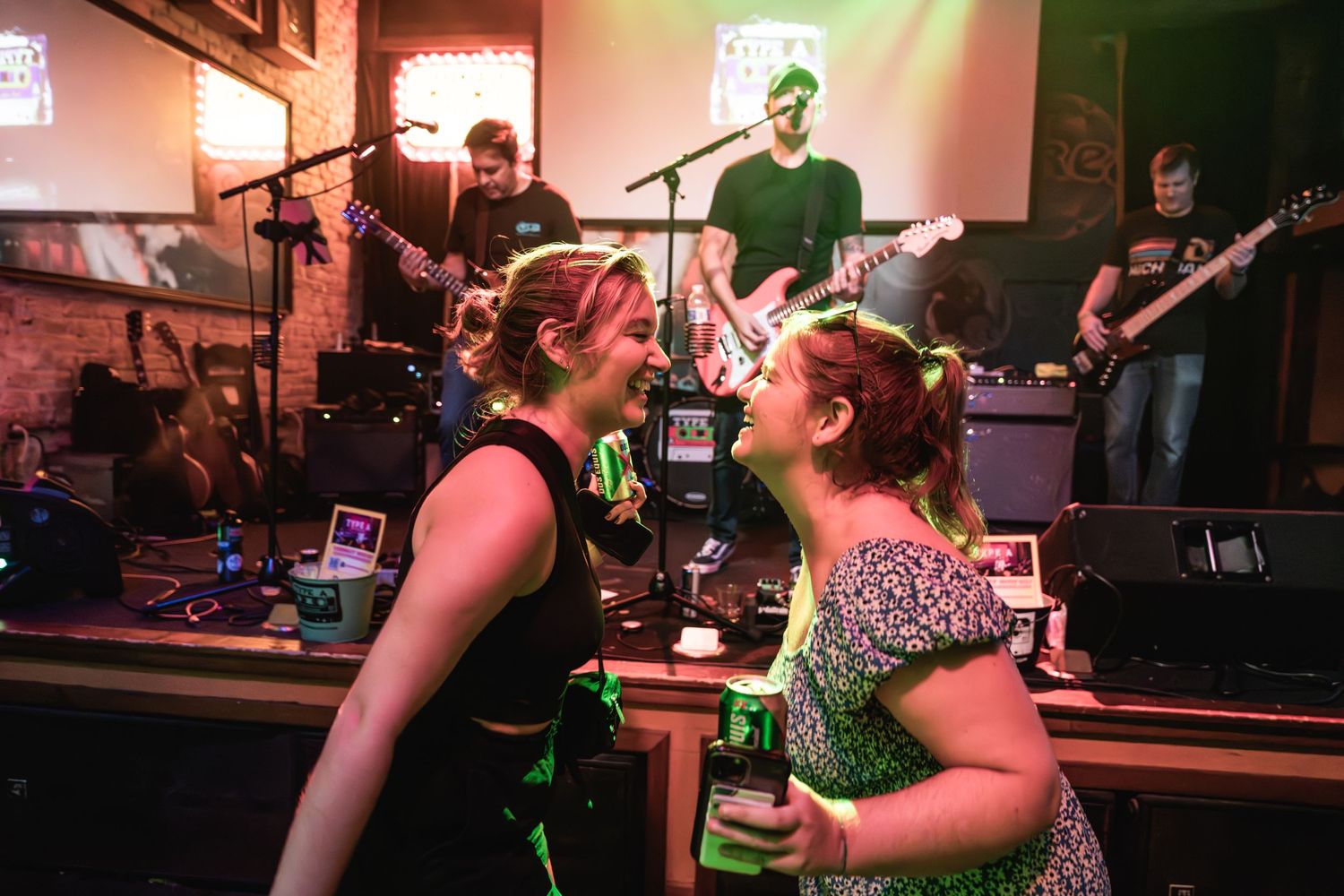Two people singing and dancing together in front of live band at music venue.