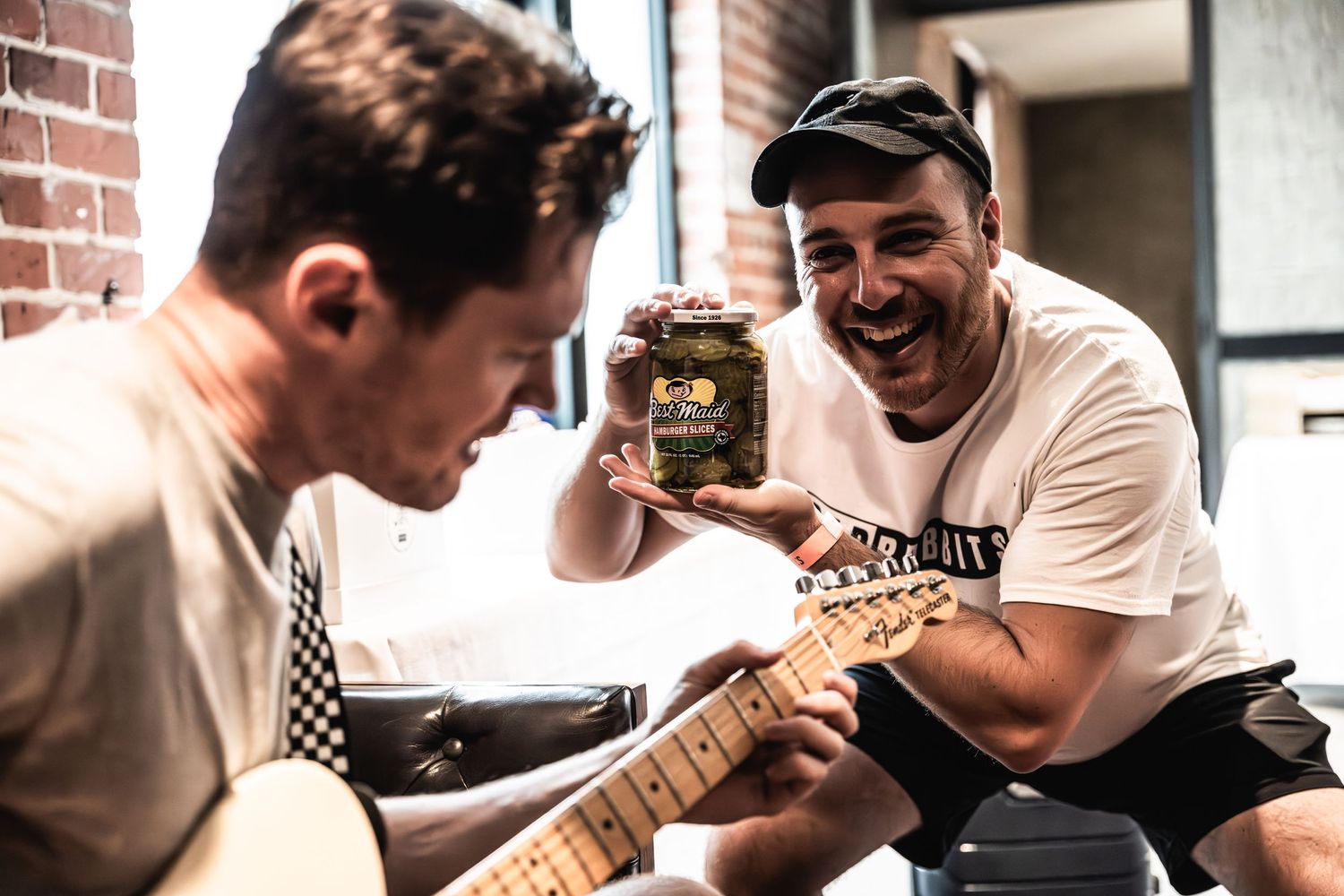 Musicians sharing a lighthearted moment during practice session with guitars.