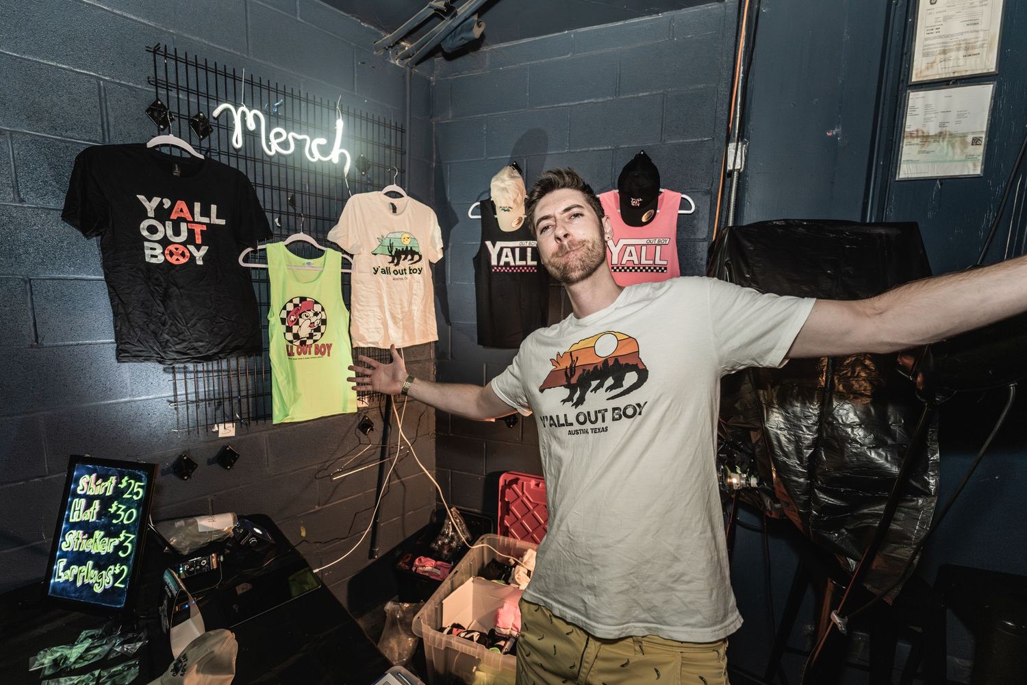 Merchandise display rack with t-shirts and apparel in a dimly lit retail space.