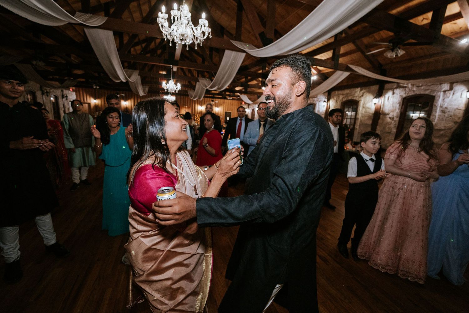 Party guests dancing together under chandelier lighting at an elegant indoor venue.