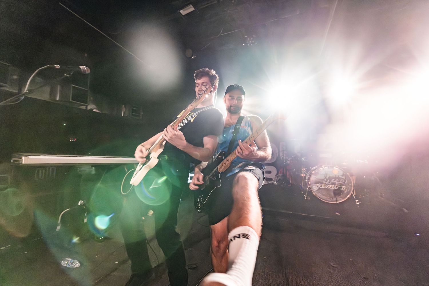 Dynamic shot of musicians performing on stage with bright backlighting effects.