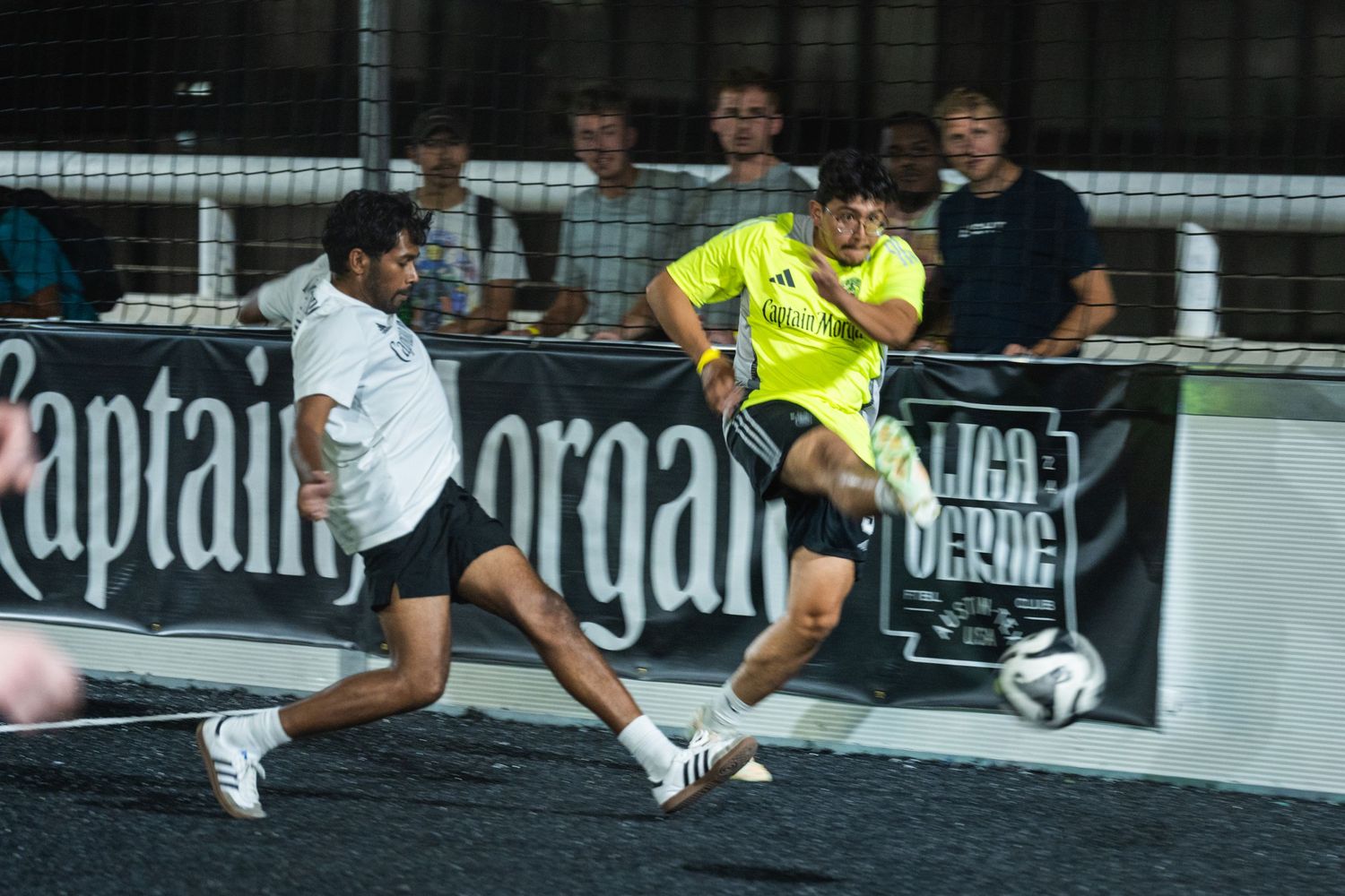 Soccer players in yellow and white uniforms battling for ball possession during match.