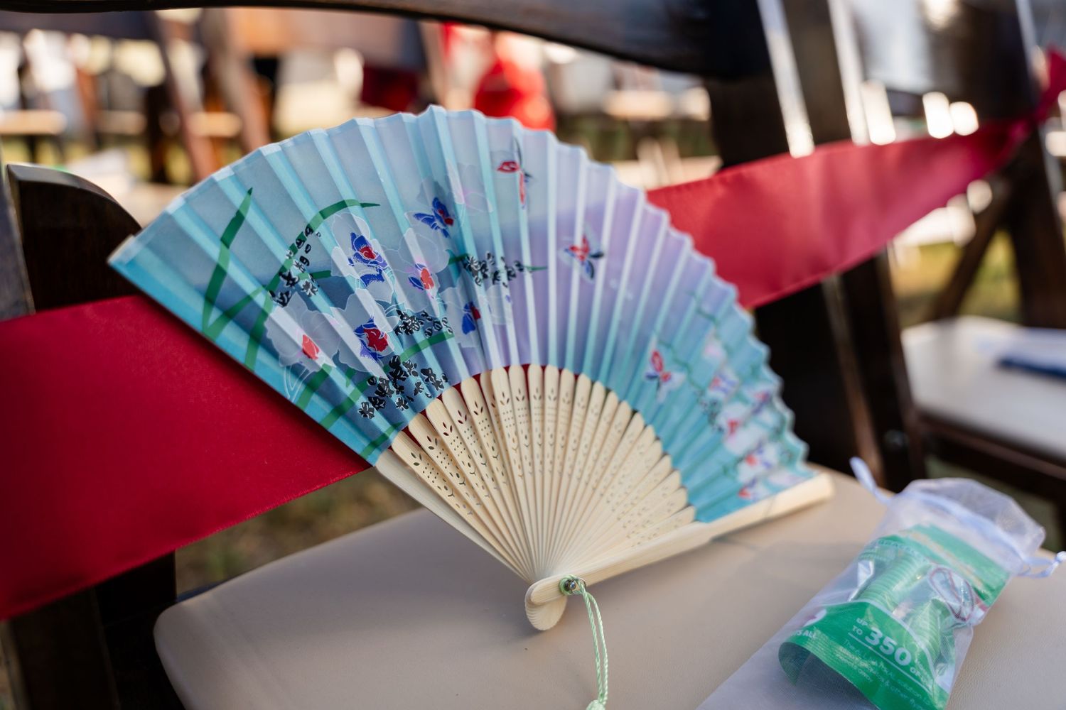 A decorative blue and white paper hand fan displayed against a red background.