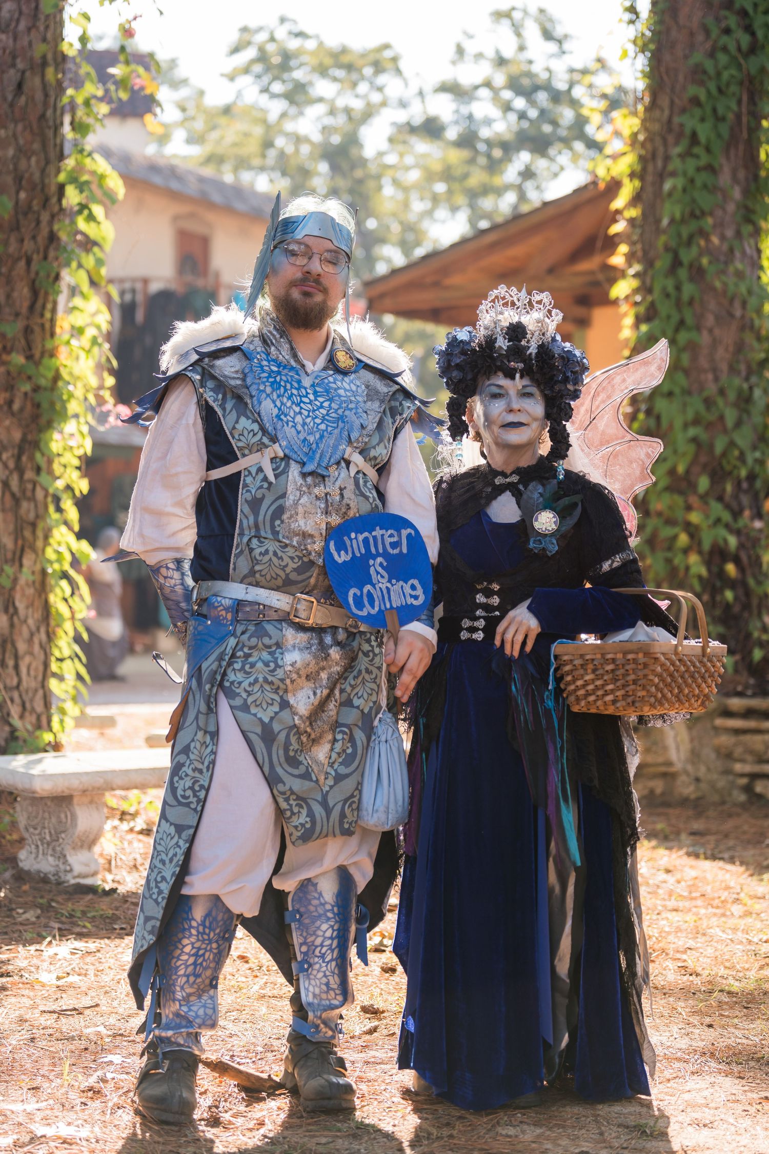 Two performers in medieval fantasy costumes posing together at a renaissance faire.