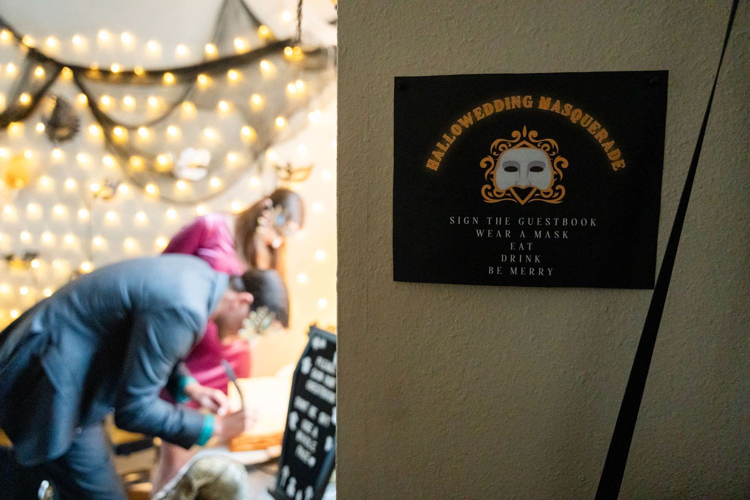 Halloween-themed event sign illuminated by string lights in the background.