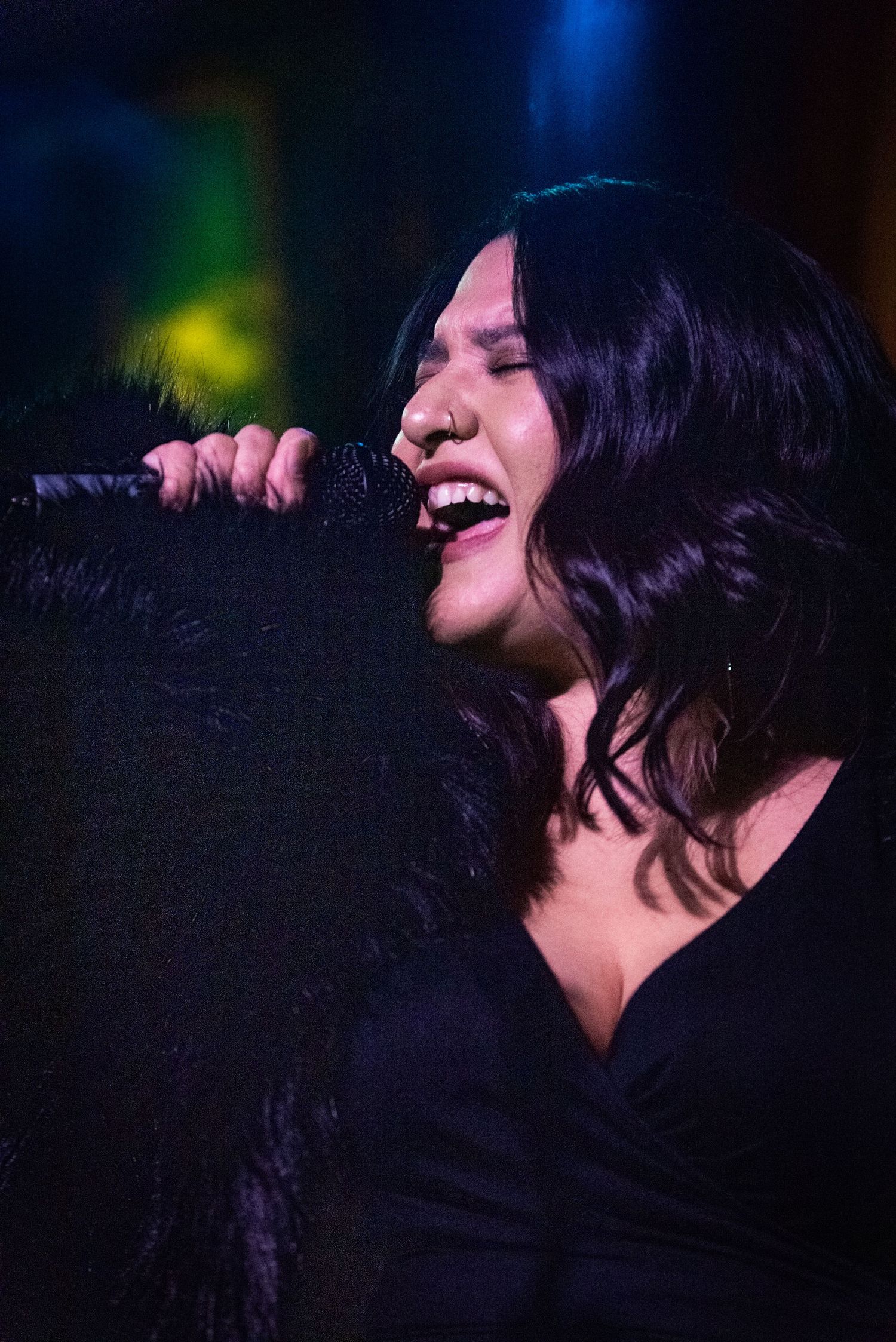 A vocalist performs passionately on stage with dramatic blue lighting.