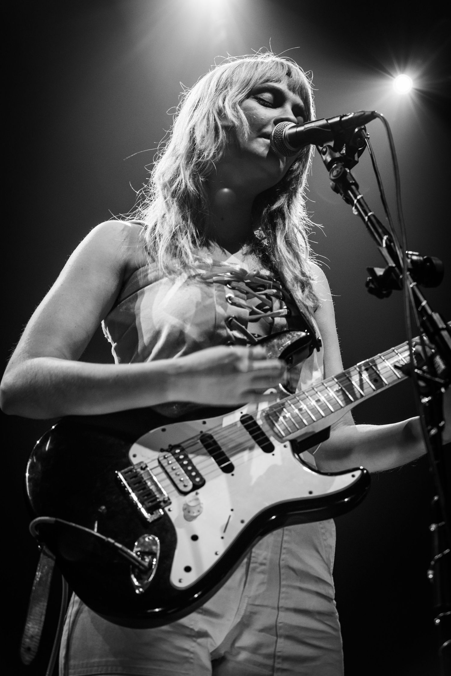 Close-up concert shot of performer singing while playing electric guitar.